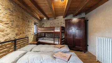 A rustic room with a bunk bed, a wooden wardrobe, and a radiator.