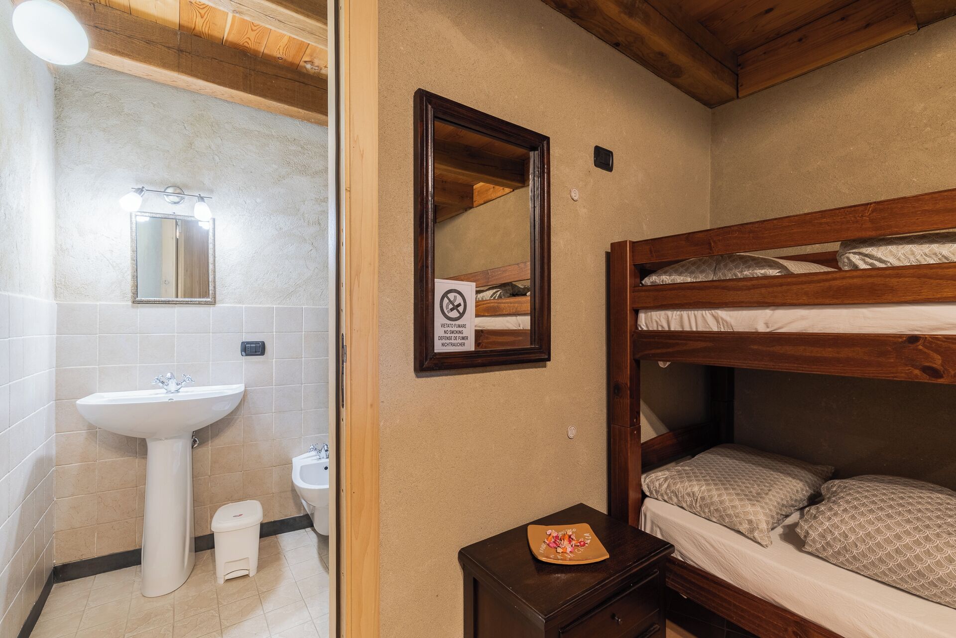 Ein Zimmer mit einem Holzbett, einem weißen Waschbecken und einem Spiegel.