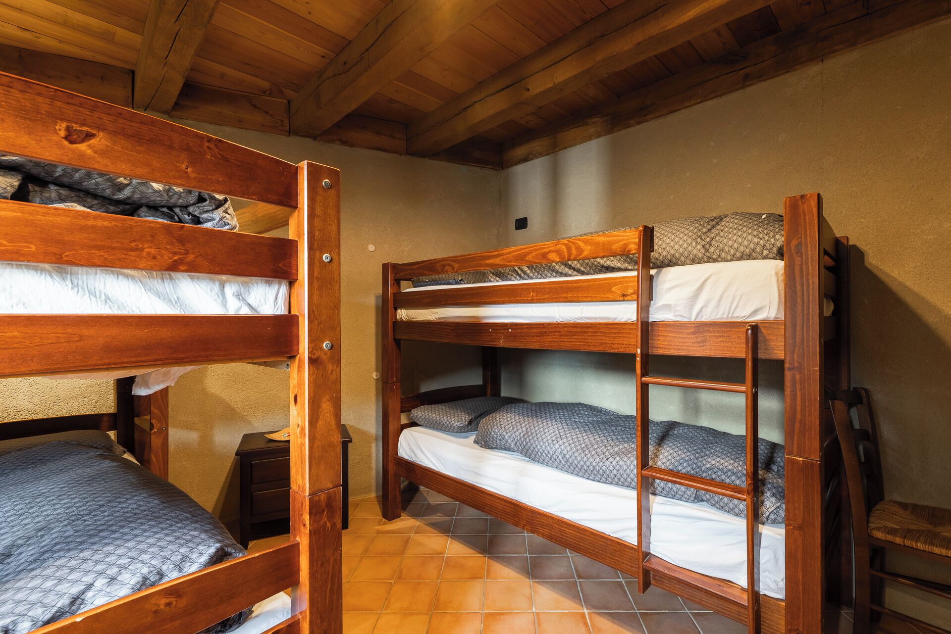 A bunk bed room with wooden frames and a tiled floor.