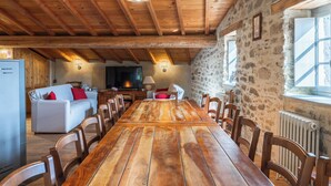 Ein rustikales Esszimmer mit Holztisch und -stühlen, einer Steinwand und einem Kamin.