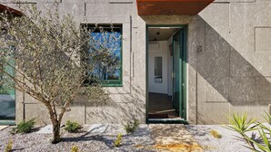 A modern building with a concrete facade, a green door, and a small tree in the foreground. - Double Room Ua06 with Shared Pool, Wi-Fi and Air Conditioning (Palmeira)