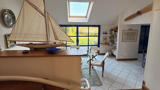 Una habitación amplia con suelo de madera, un velero de juguete en un escritorio, un tragaluz y vistas al exterior.