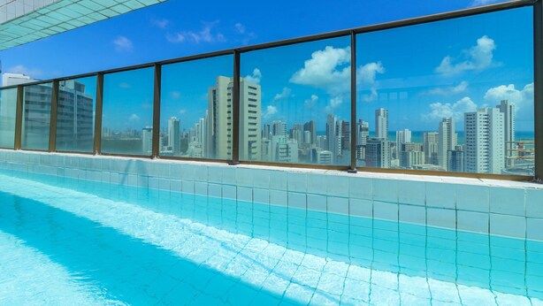 Una piscina con vista a un paisaje urbano a través de amplios ventanales.