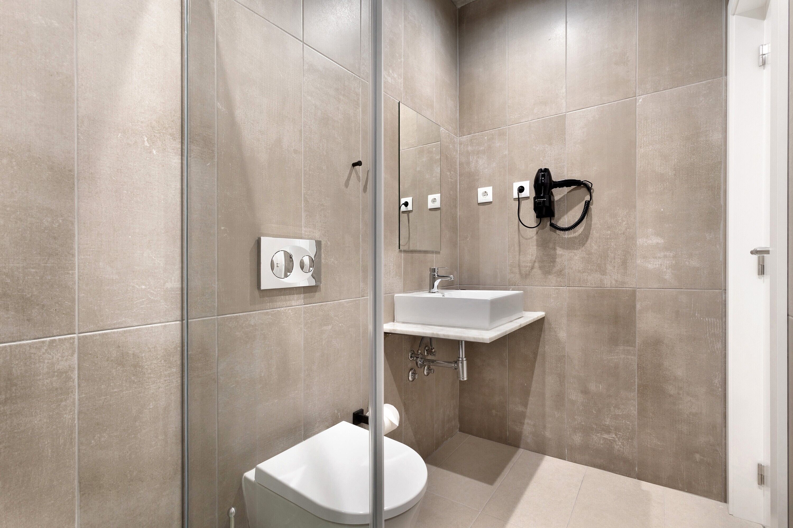 A modern bathroom with a glass shower enclosure, a white sink, and a mirror.