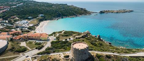 A coastal town with a prominent tower, a beach, and surrounding greenery.