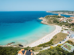 An aerial view of a coastal area with a beach, buildings, and a rocky coastline. - Accommodation 1 km From the Beach (Santa Teresa di Gallura)