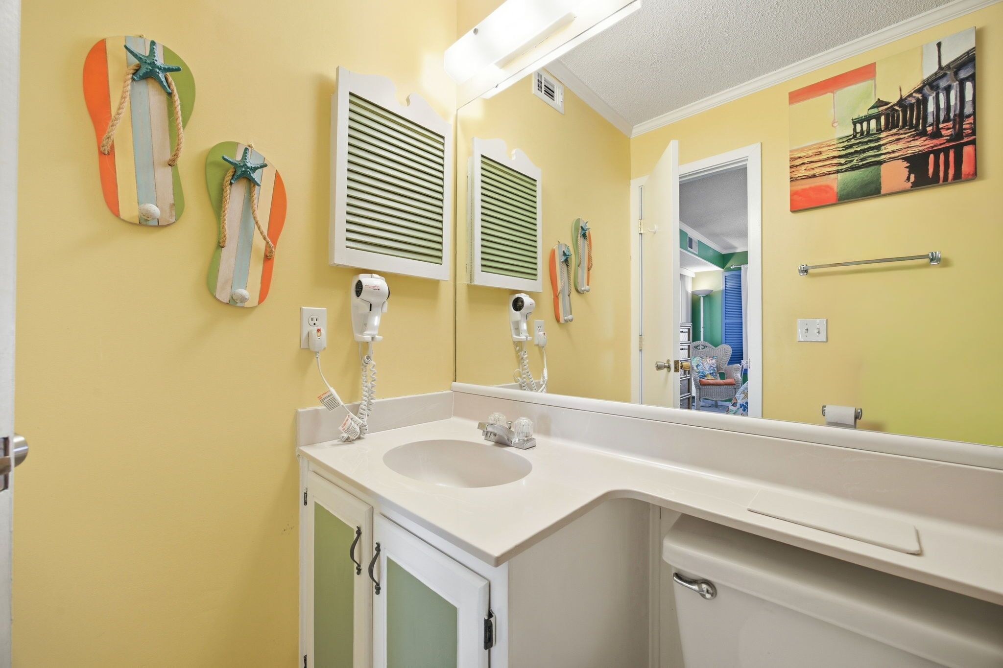 A bathroom with a sink, two hair dryers, and a mirror.