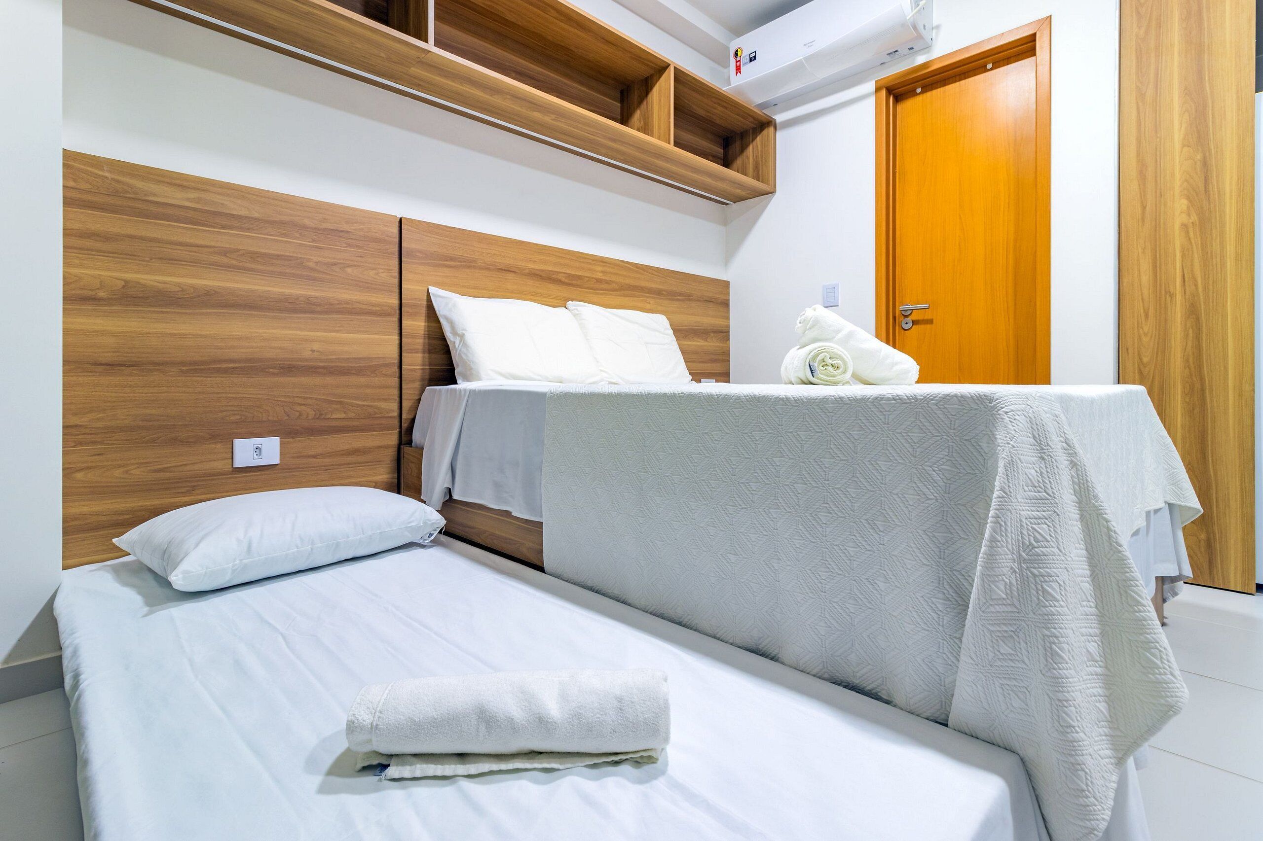 Une chambre à coucher avec une tête de lit en bois, un lit avec une literie blanche, une table de chevet et une armoire en bois.