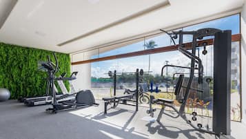 Uma academia com equipamentos de exercícios, uma parede verde e uma grande janela com vista para o exterior.