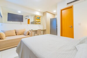 Een hotelkamer met een bed, een bank, een bureau, een televisie en een koelkast.