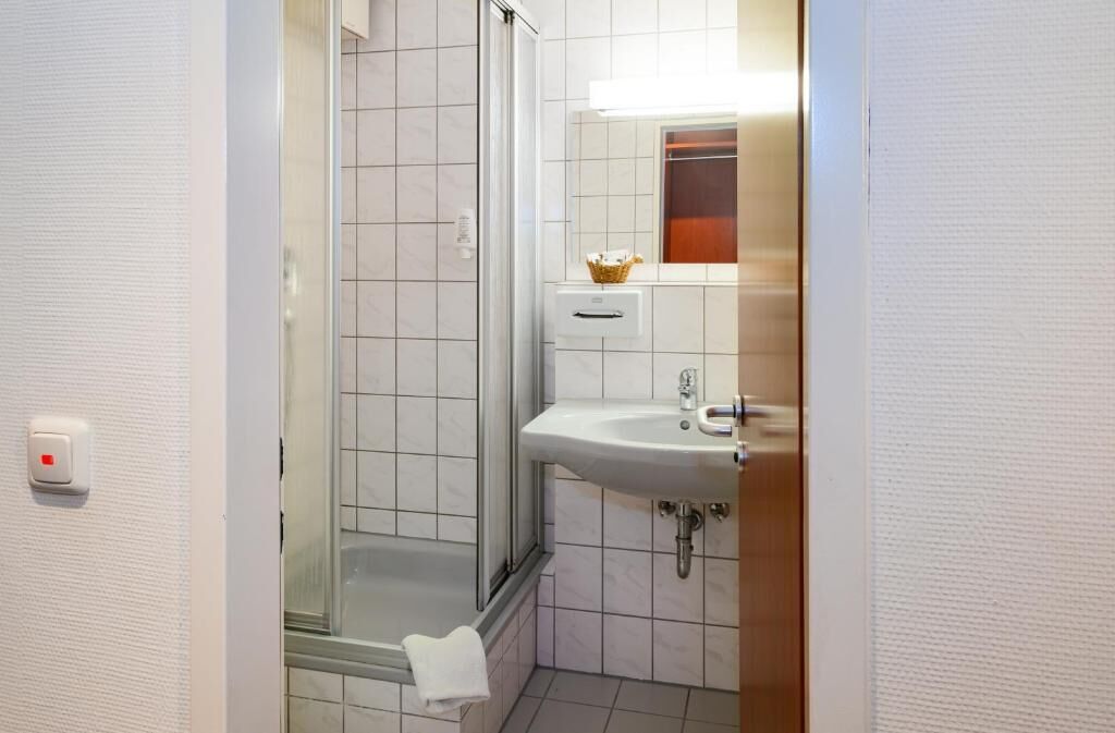 A bathroom with a glass-enclosed shower, a sink, and a mirror.