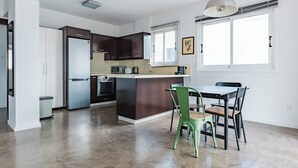 Eine moderne Küche mit dunklen Schränken, einer zentralen Kochinsel und einem Essbereich mit Tisch und Stühlen.