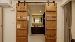 Una puerta corredera de madera con estantes integrados que contienen libros y objetos decorativos.