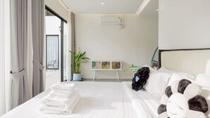 Habitación de hotel con cama, una ventana grande con cortinas, una planta en maceta y un aire acondicionado instalado en la pared.