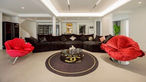 Una sala de estar moderna con un sofá seccional, dos sillas rojas y una mesa de centro con el logotipo de Chanel.