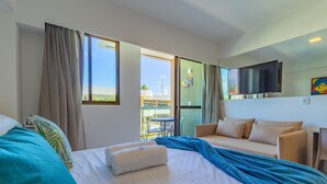 Ett hotellrum med en säng, en soffa, en TV och en balkong med utsikt över staden.
