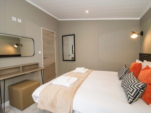 Een hotelkamer met een bed, nachtkastje, spiegel en een wandlamp.
