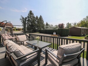 Een terras met buitenmeubilair, een hangstoel en een tafel met een bloevas.