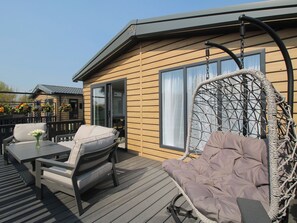 Een terras met buitenmeubilair, waaronder een stoel en een tafel, en een hangstoel.