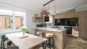 Een moderne keuken met houten kasten, een groot eiland en een eethoek met stoelen.