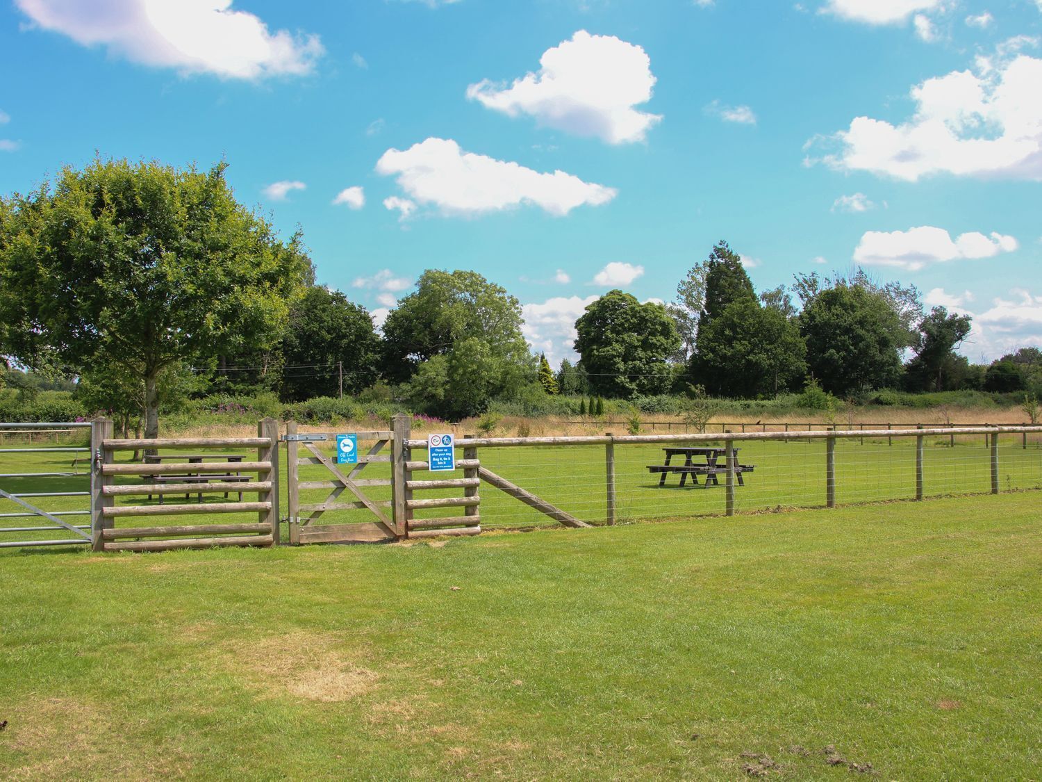 A fenced outdoor area with picnic tables and a gate.