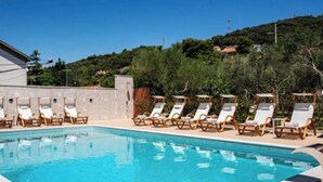 A swimming pool with lounge chairs and a building in the background. - Apartments Foric (Rab)