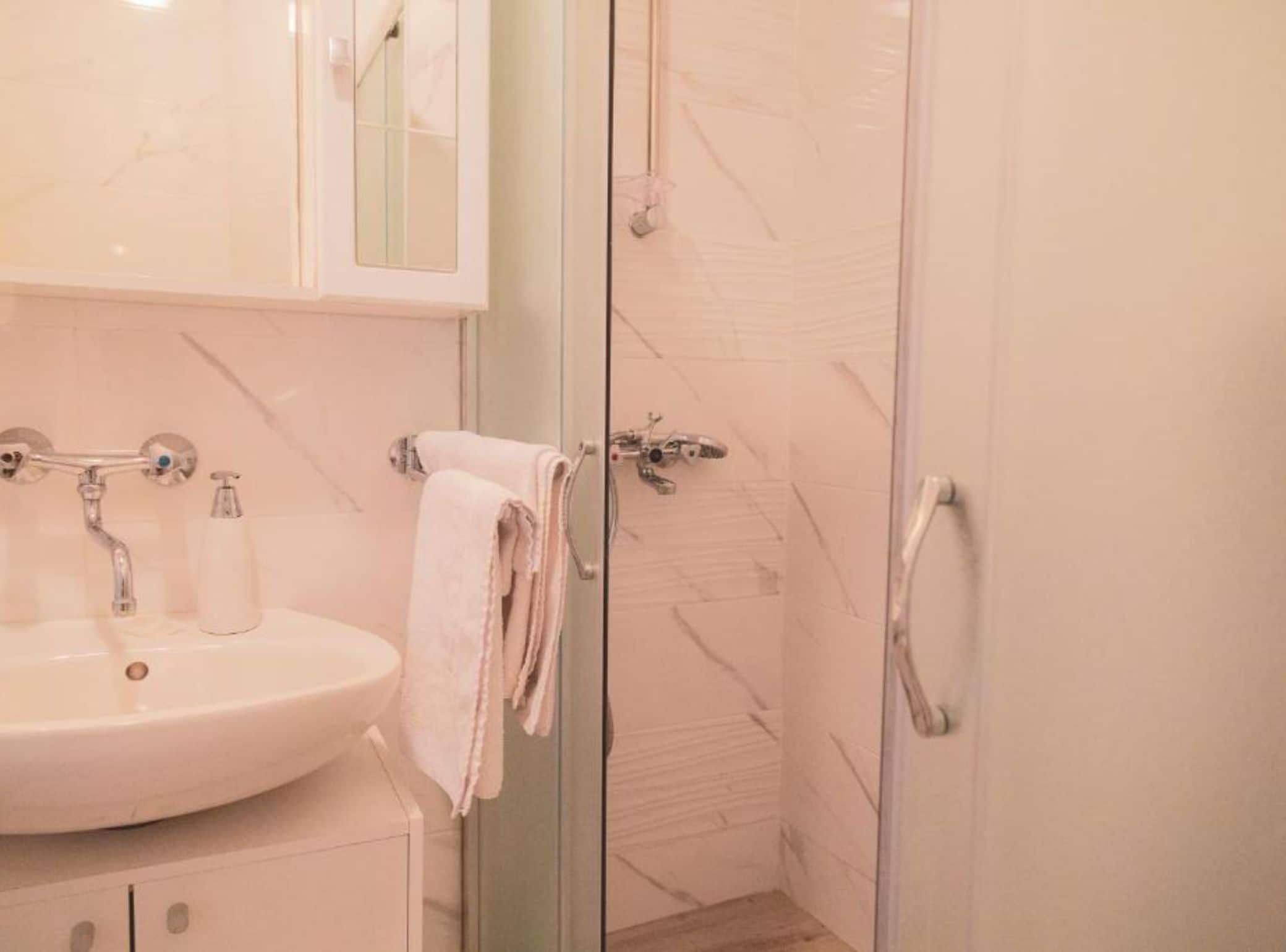 A bathroom with a sink, mirror, and glass shower enclosure.