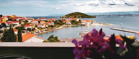 A coastal town with red-roofed buildings, a marina, and a clear view of the sea.