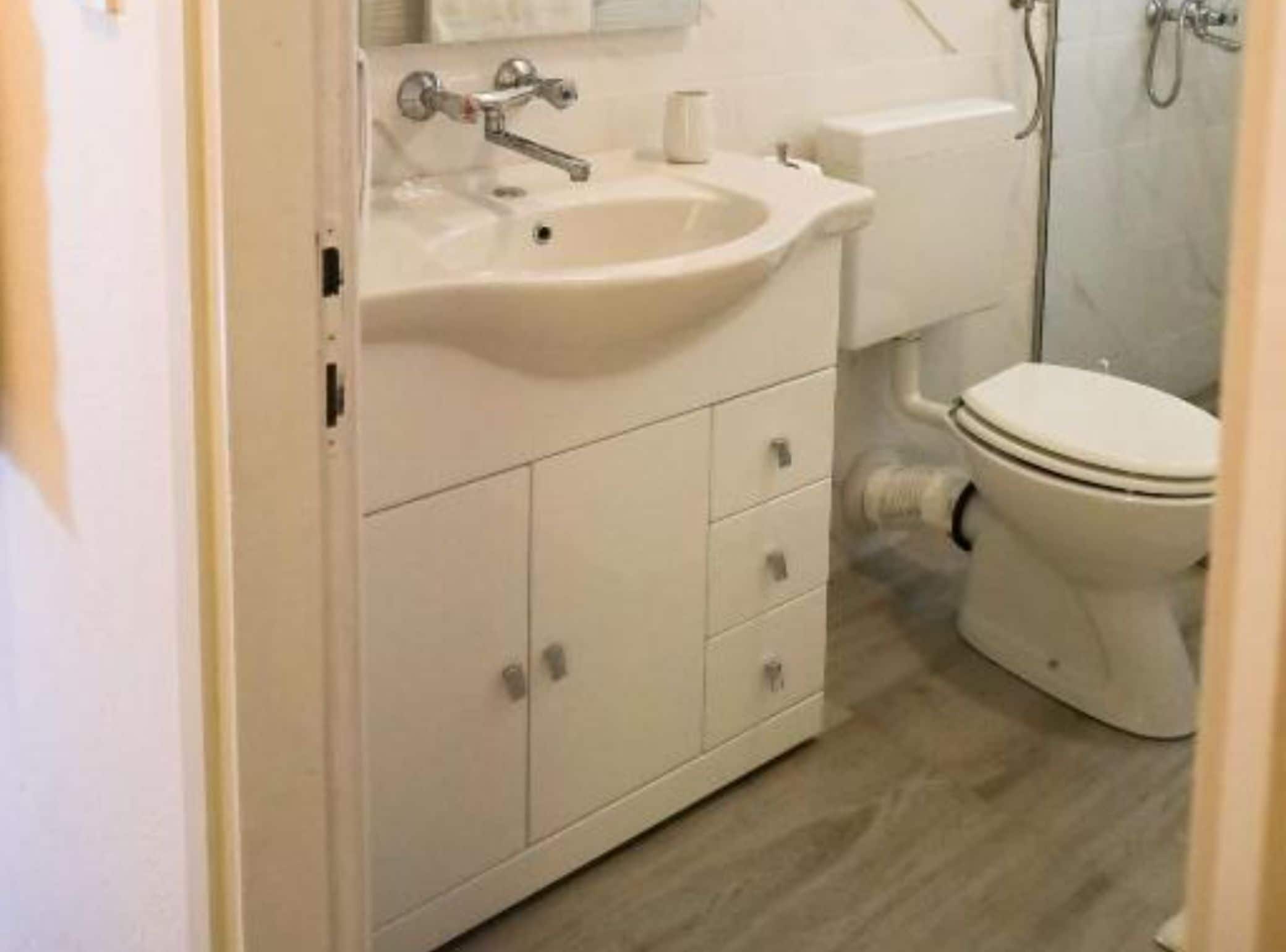 A bathroom with a white sink, a toilet, and a shower area.