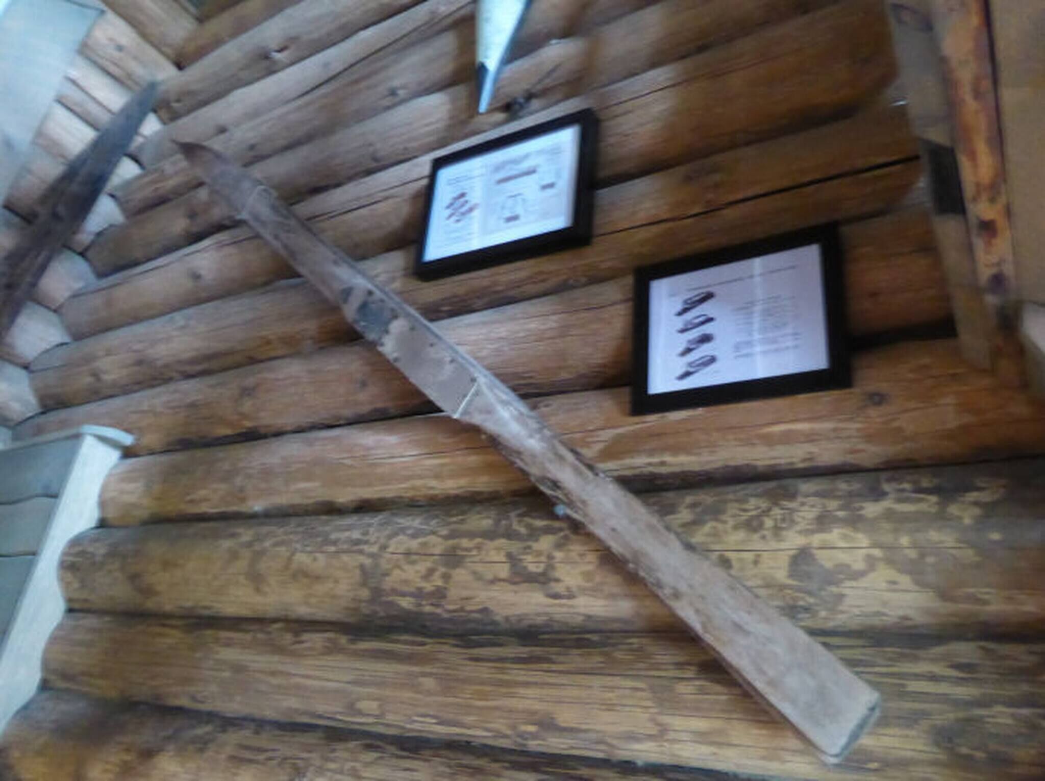 Una cabaña de troncos de madera con dos carteles informativos en la pared.