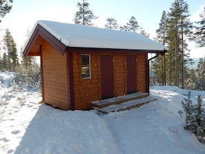 A small wooden cabin with a snow-covered roof, surrounded by trees. - Dalpilen a Great Timber Lodge Middle and Loft Floors (Idre)