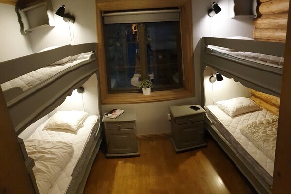 Una habitación pequeña y acogedora con dos literas, un ventanal y mesitas de noche con lámparas.