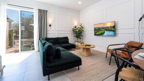 A modern living room with a sectional sofa, a round coffee table, and a TV mounted on the wall. - Sunny Dreams Vacation Home 3 miles to Disney 7574 (Kissimmee)