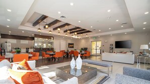 A spacious hotel lobby with a modern design, featuring a central coffee table, seating area, and a television. - Sunny Dreams Vacation Home 3 miles to Disney 7574 (Kissimmee)