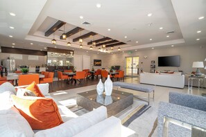 Eine großzügige Hotelhalle mit modernem Design, inklusive eines zentralen Couchtisches, einer Sitzecke und einem Fernseher.