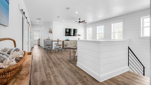 A spacious kitchen with white cabinetry, a dining area with stools, and a large window providing natural light. - Latitude! New! 8 Bed! Beach! (Destin)