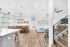 Una cocina amplia con una isla central, piso de madera y luminarias modernas.