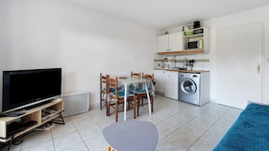Ein kompakter Wohnraum mit Fernseher, Esstisch, Stühlen, Waschmaschine und einer Couch.