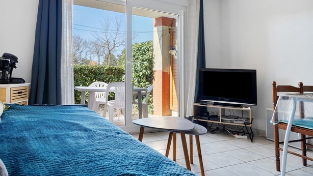 Ein Zimmer mit einem Bett, einem Fernseher, einem kleinen Tisch und einem Stuhl.
