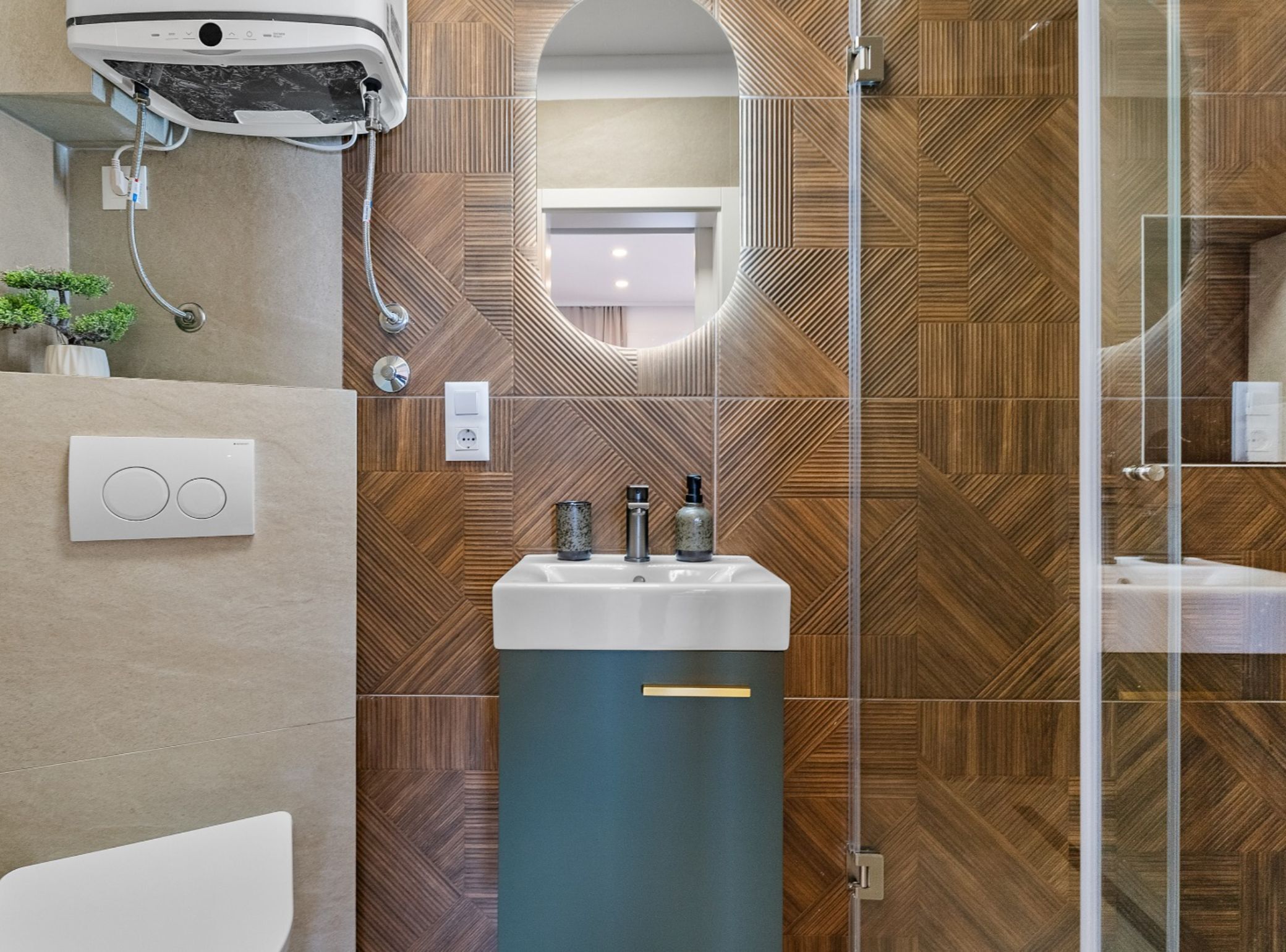 Ein modernes Badezimmer mit Wandverkleidung im Fischgrätmuster aus Holz, einem Mittelwaschtisch mit zwei Flaschen und einem Spiegel darüber.