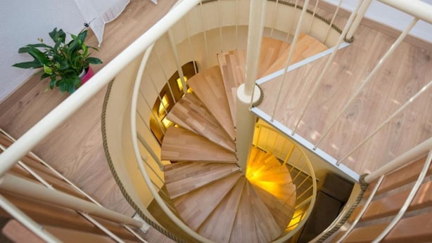 Un escalier en colimaçon avec des marches en bois et des rampes blanches.
