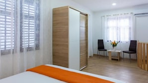 Une chambre d’hôtel comprenant un lit, une armoire en bois, un bureau avec deux chaises et une fenêtre avec des rideaux.