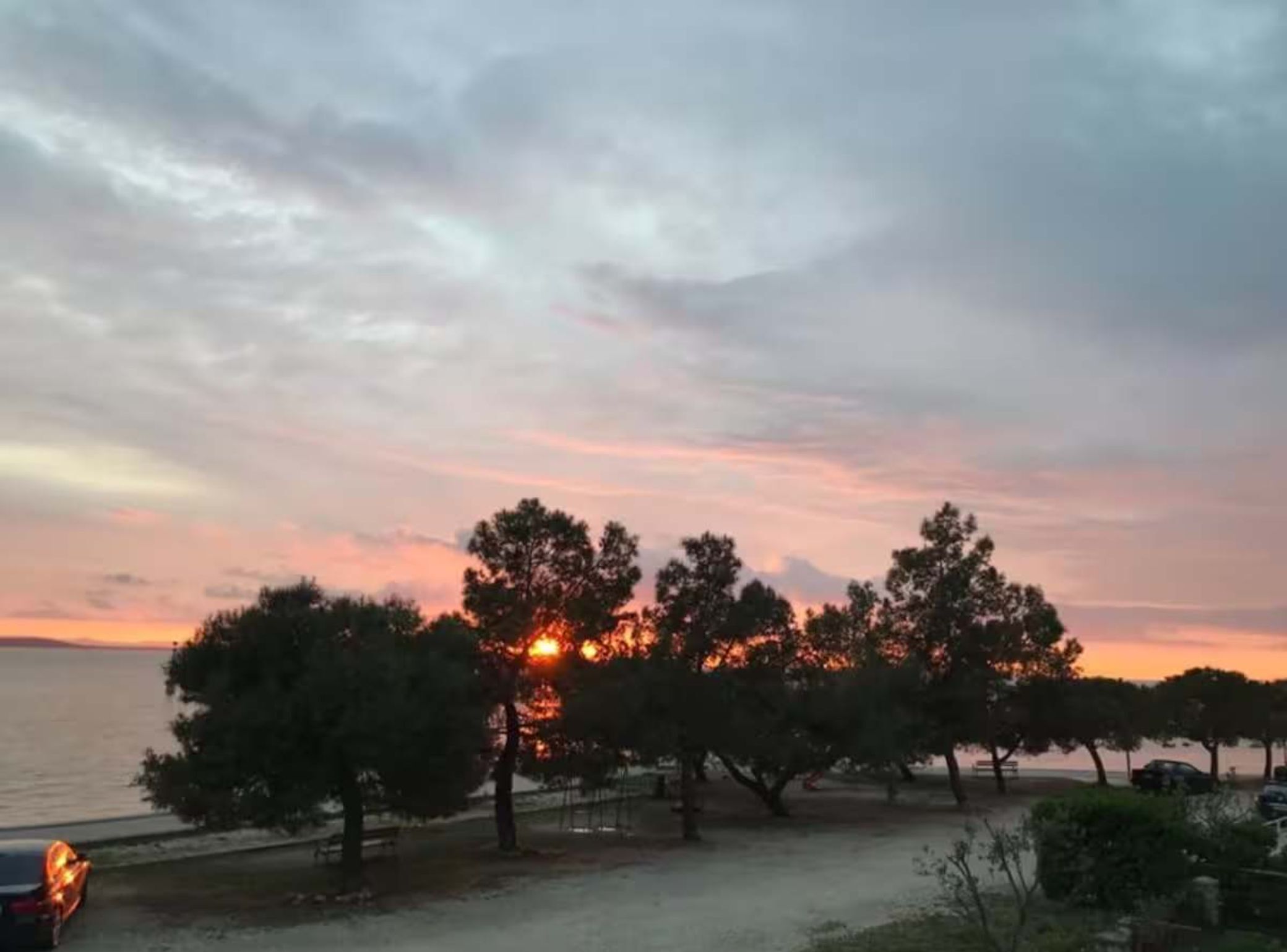 A sunset over a body of water with trees in the foreground.