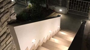A staircase with a stone wall on one side and a white wall on the other, leading to a gated area. - Apartments Blue Horizon Retreat (Zadar)
