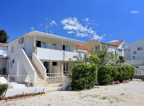 A two-story building with a staircase leading to the entrance, surrounded by greenery and a gravel driveway. - Apartments Blue Horizon Retreat (Zadar)