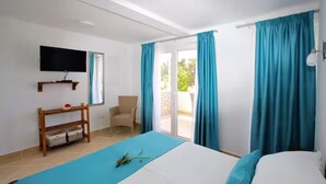 A bedroom with a bed, a chair, a TV, and a balcony with curtains. - Apartments Blue Horizon Retreat (Zadar)