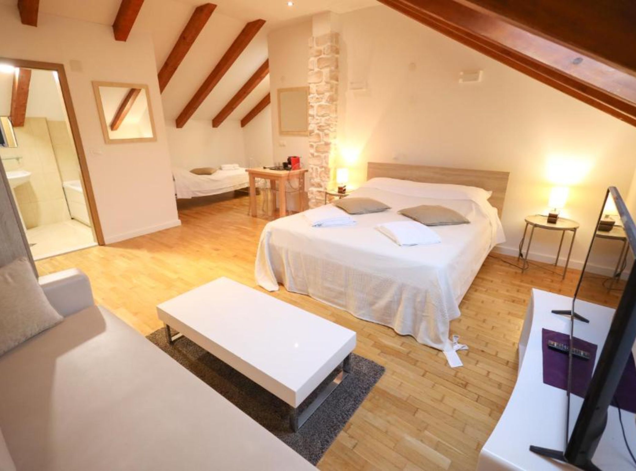 Une chambre à coucher avec un grand lit, une table de chevet, une chaise et un téléviseur.