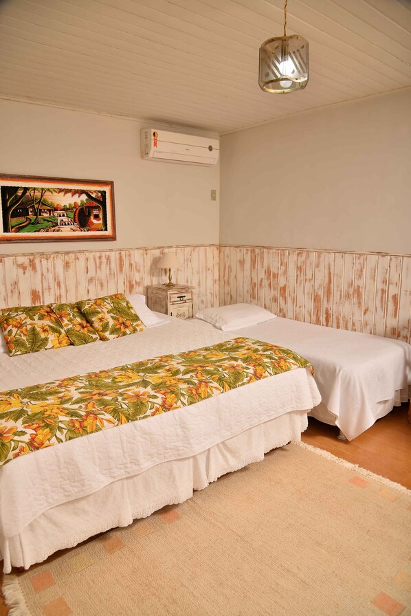 A bedroom with two beds, a hanging light fixture, a painting, and an air conditioning unit. - HOTEL SOLAR FAZENDA DO CEDRO (Areal)