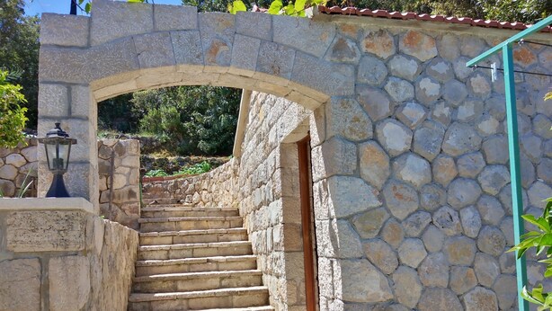 Un escalier en pierre menant à une porte, entouré de murs de pierre et d’une lanterne.