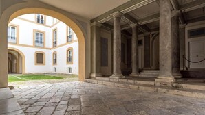 A courtyard with stone flooring and columns, surrounded by buildings with arched windows. - Dimora Torremuzza historic home downtown Palermo with three bedrooms and 4 bathrooms (Palermo)